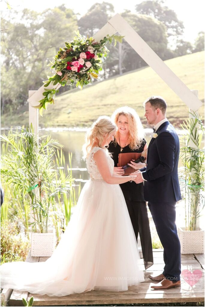Liz & Jarrod picked a September wedding date - Bride and groom smiling and holding hands while Lynette Maguire marriage celebrant officiates their ceremony