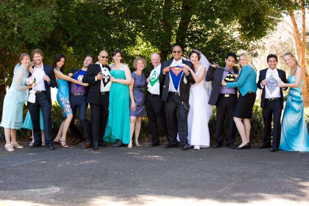 Groom and males guests with superhero tshirts under their shirts being revealed by their female partners