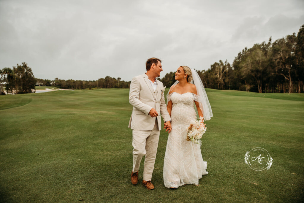 Elope on beautiful Bribie - Bride and groom walking on golf course holding hands and smiling at each other