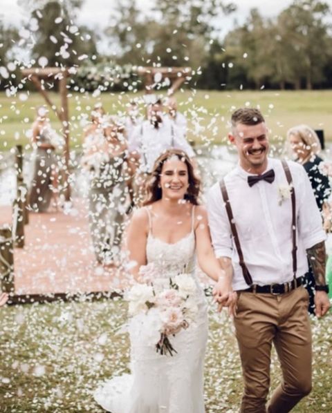 bride and groom laughing while walking back down the aisle to a sea of confetti