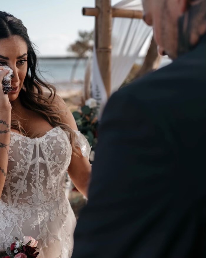 Close up of bride wiping tears as the groom reads his vows