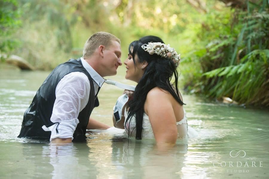 Trash the dress fun - Bride and groom in bridal attire kissing in the water