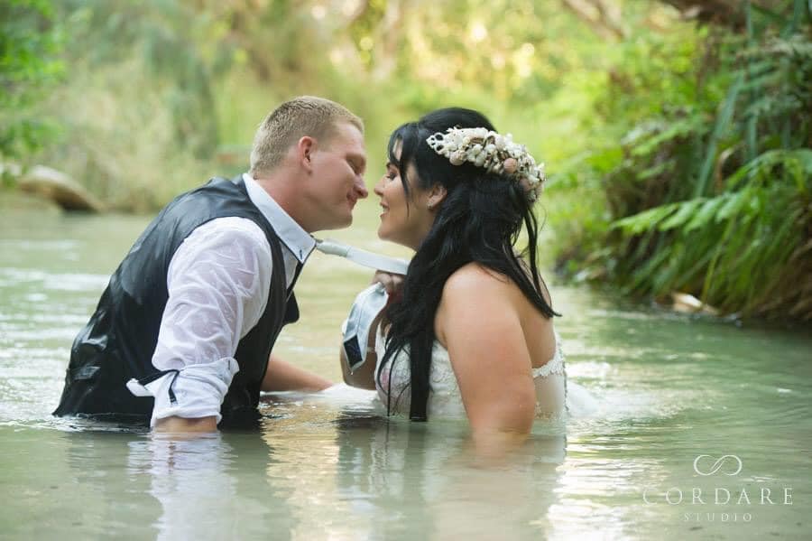 Bride and groom in bridal attire kissing in the water