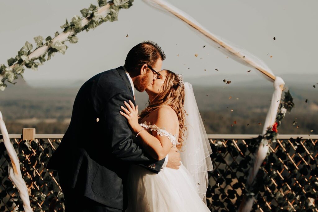 Bride and groom kissing with mountains in the background 