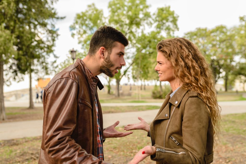 Man and woman in a park arguing using hand gestures