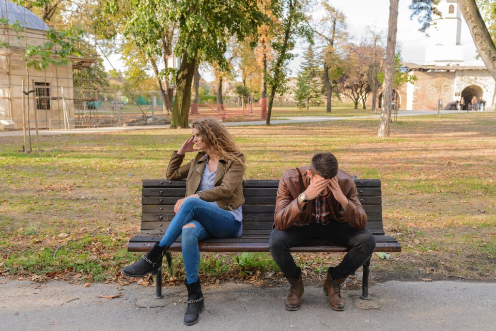 Man and woman on park bench facing away from each other in contemplation