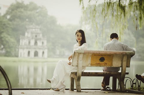 man and woman on opposite ends of a bench facing away from each other