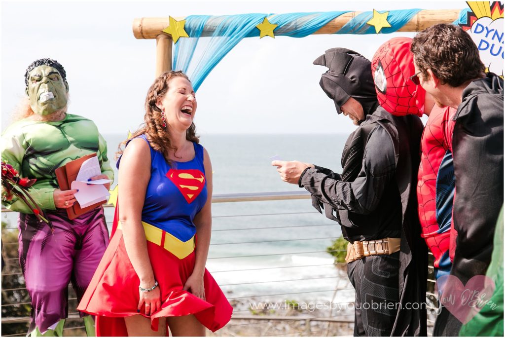 Batman reading his vows as Supergirl laughs out loud and The Hulk (Lynette Maguire Marriage Celebrant) looks on 