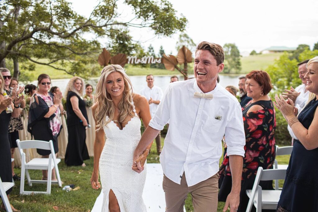 Smiling bride and groom walking back down the aisle as husband and wife