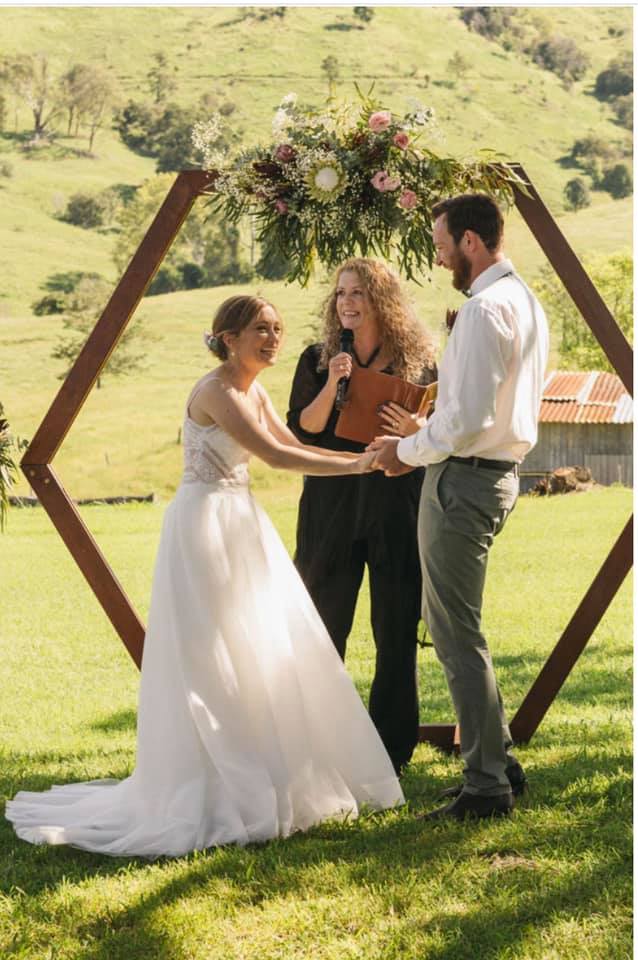 Bride and groom laughing as celebrant Lynette Maguire speaks with microphone