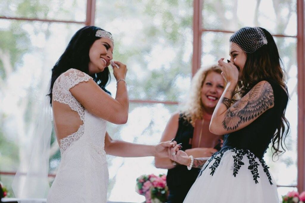 Two brides laughing while being married by Lynette Maguire