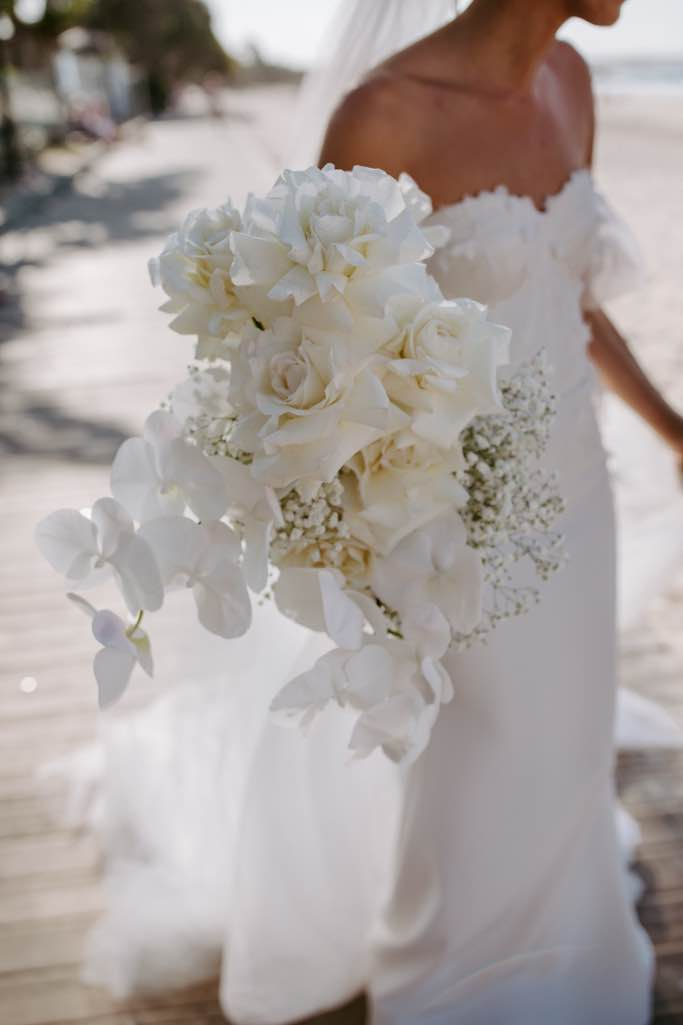a stunning white bouquet with roses orchids and babys breath 