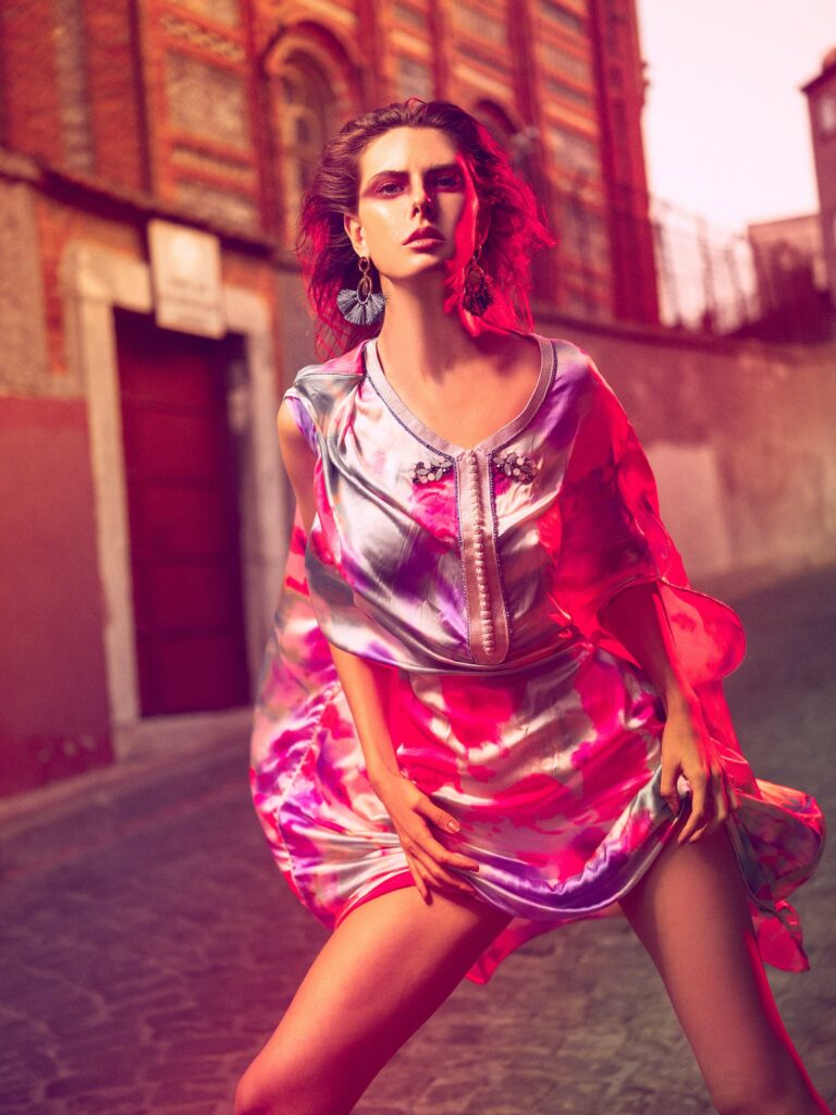 Woman wearing micro dress in pink hues in an alleyway