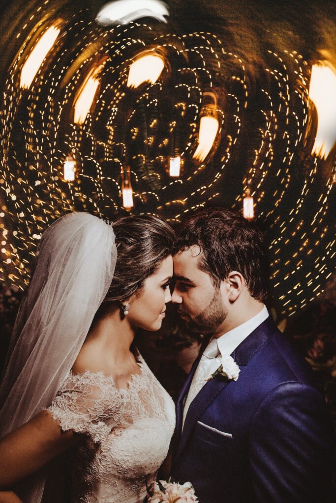 Bride and groom foreheads touching with camera distorting the background lights